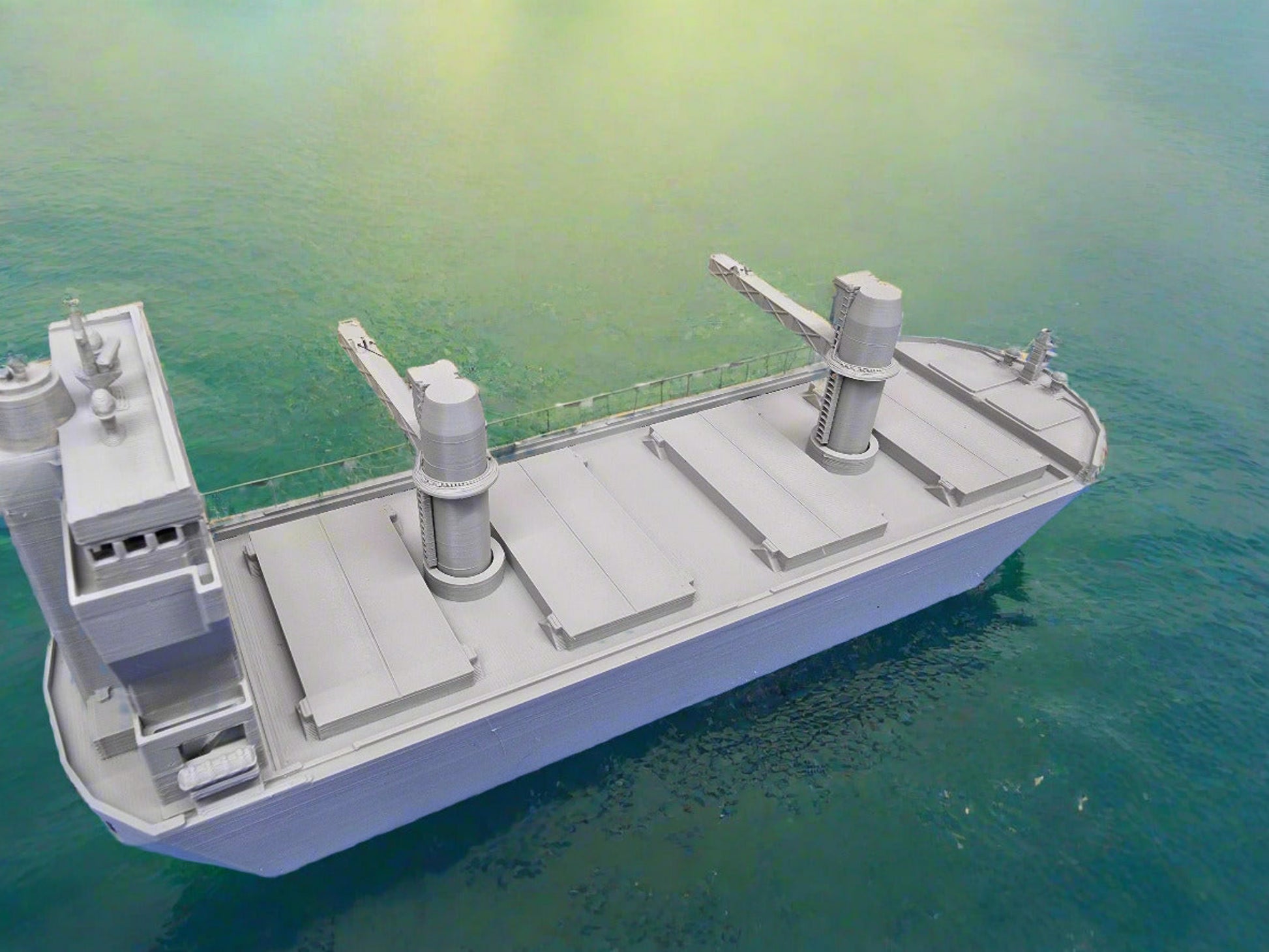 Model cargo ship on a blue surface with a forest background