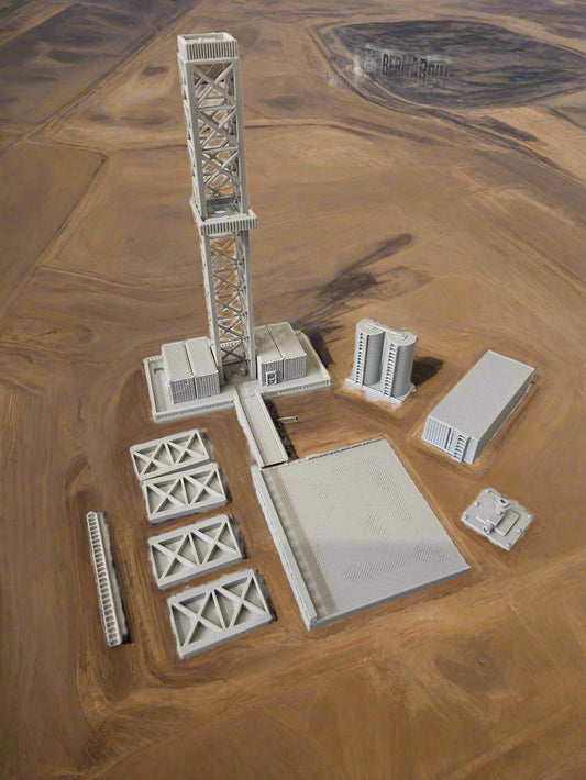 Model train tracks and infrastructure pieces on a light gray surface