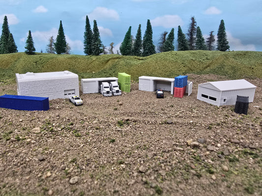 Model of a small town with buildings and vehicles on a textured surface with trees in the background.