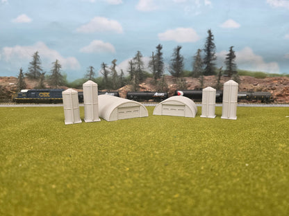 Model train scenery with small buildings and trees on a grassy field