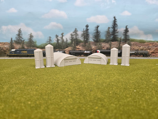 Model train scenery with small buildings and trees on a grassy field