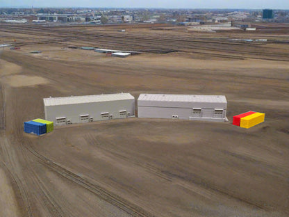 Model of two gray buildings with colorful containers on a model landscape with trees and sky.